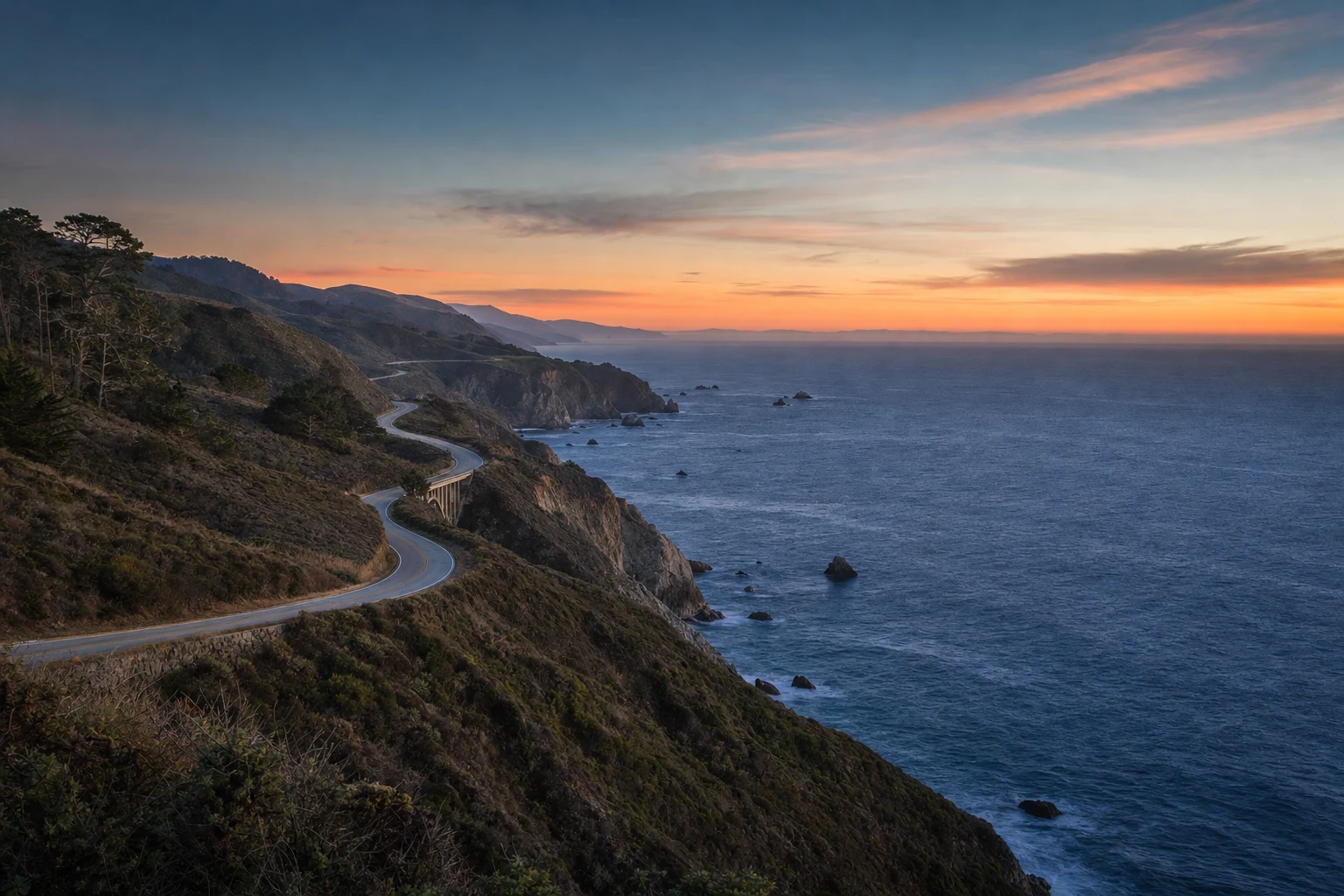 Carretera costera de California al azul del anochecer sobre un océano cobalto con horizonte melocotón