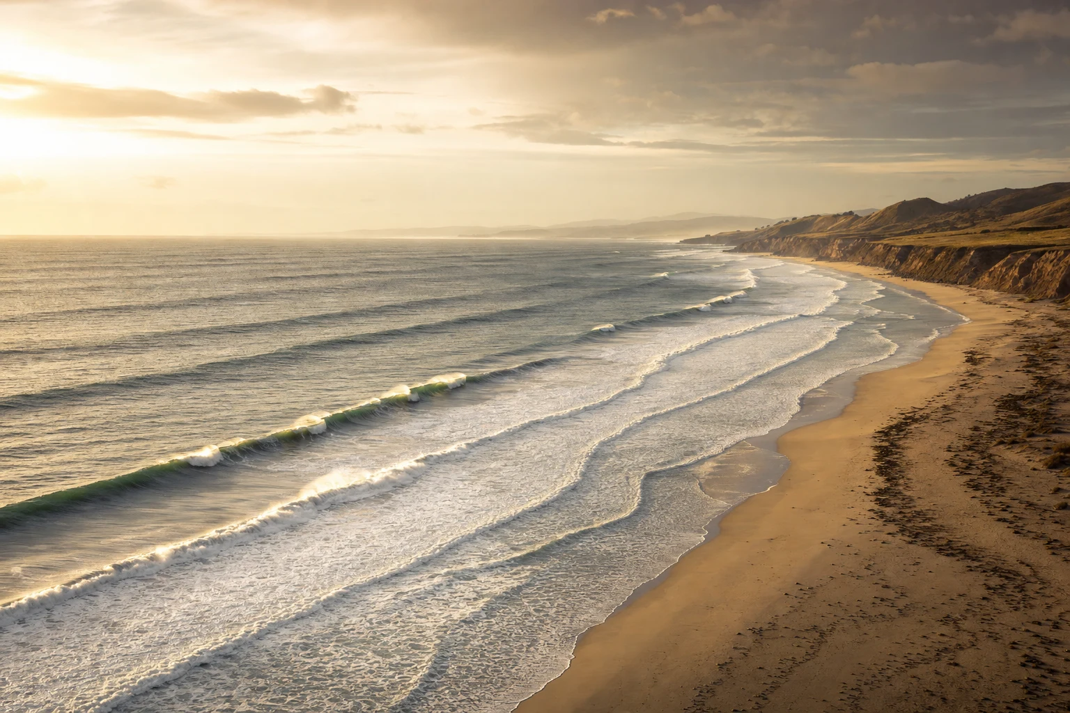 Repeating waves seen from above along a golden beach, with clean natural rhythm and layered shoreline texture.