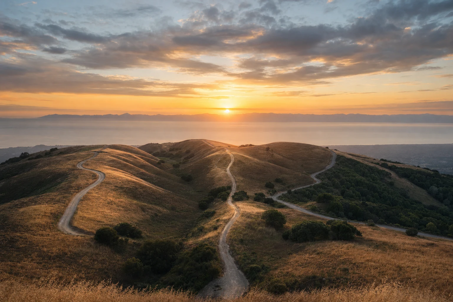 Aerial view of three winding paths crossing separate hills toward a shared horizon