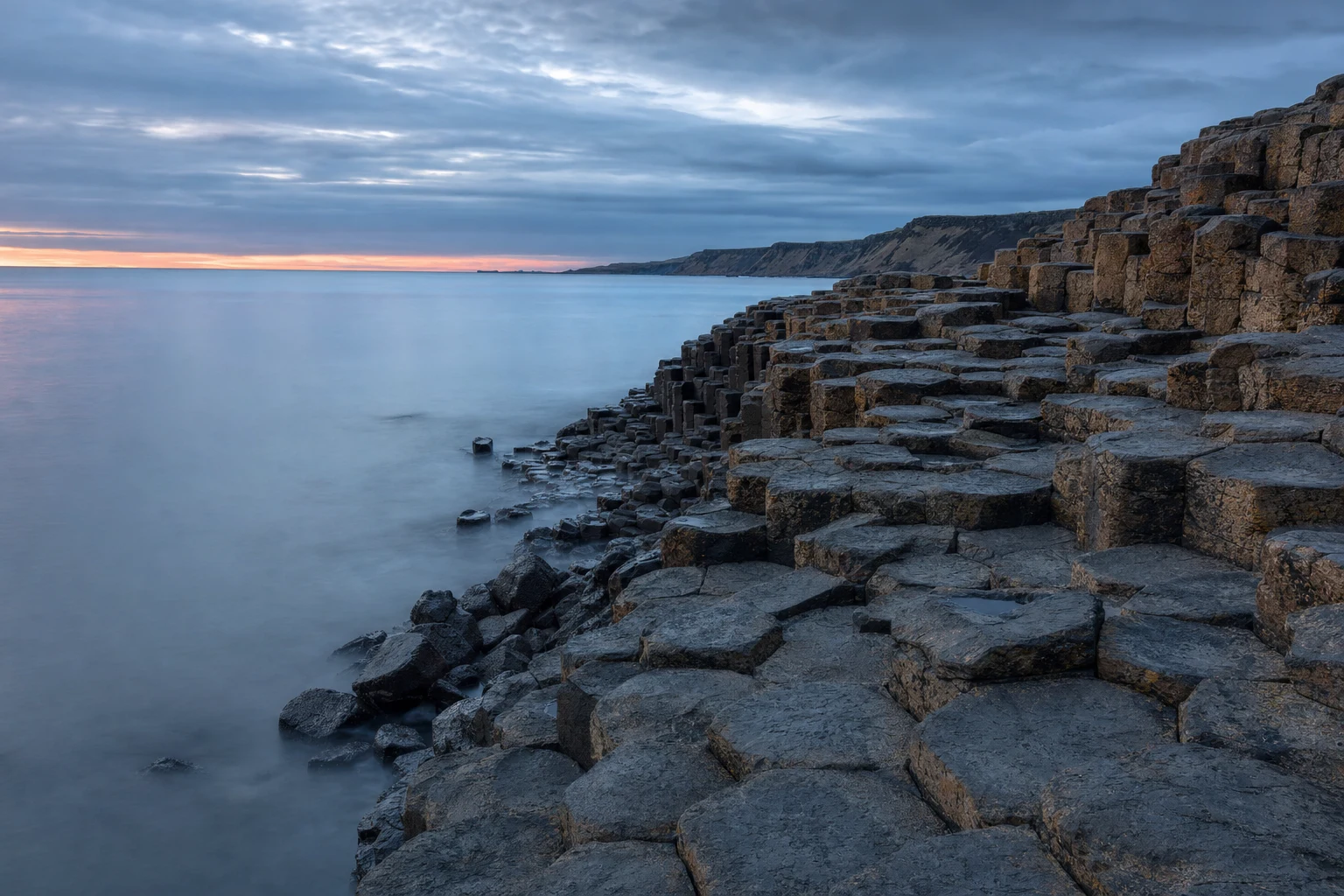Pilares de basalto estratificados junto a un mar Atlántico en calma al amanecer, con tonos azul grisáceos
